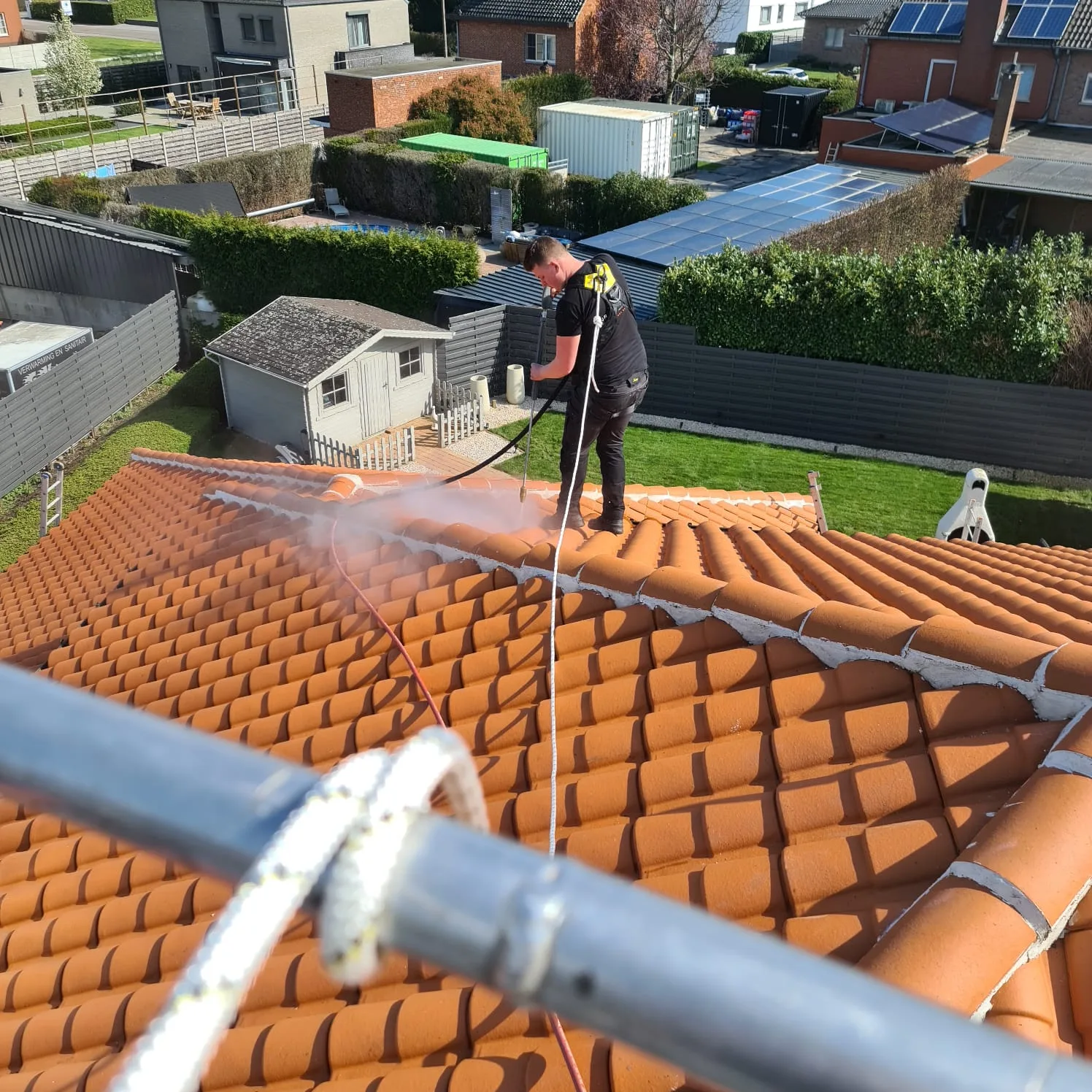 Een ervaren werkman van Group JRS voert dakreiniging uit, verwijdert mos en vuil voor een schoon en goed onderhouden dak.